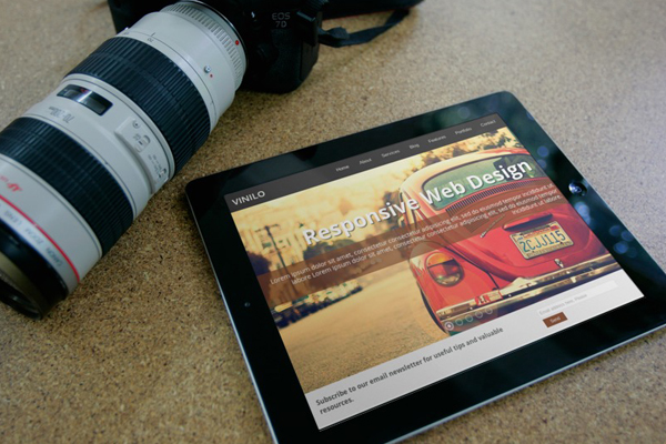 Tablet showing a responsive website beside a camera lens, illustrating the cost to build an app for a small business